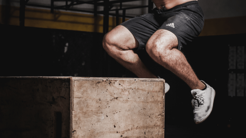 A person jumping over a wooden box in a gym