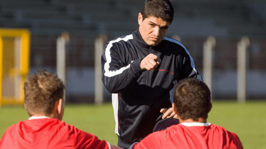 a soccer coach talking to players on the field