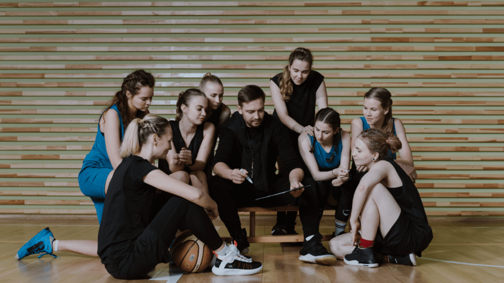 a group of people sitting on a basketball court