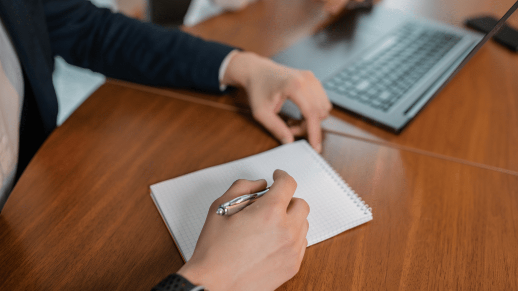 a person is writing in a notebook while sitting at a desk