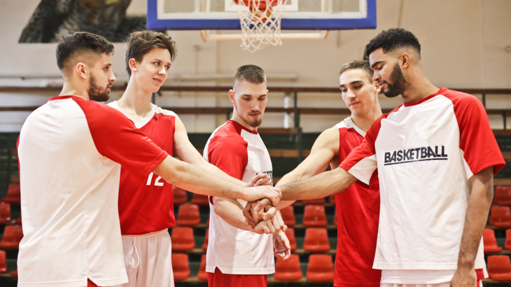 a group of people holding hands together in a basketball game