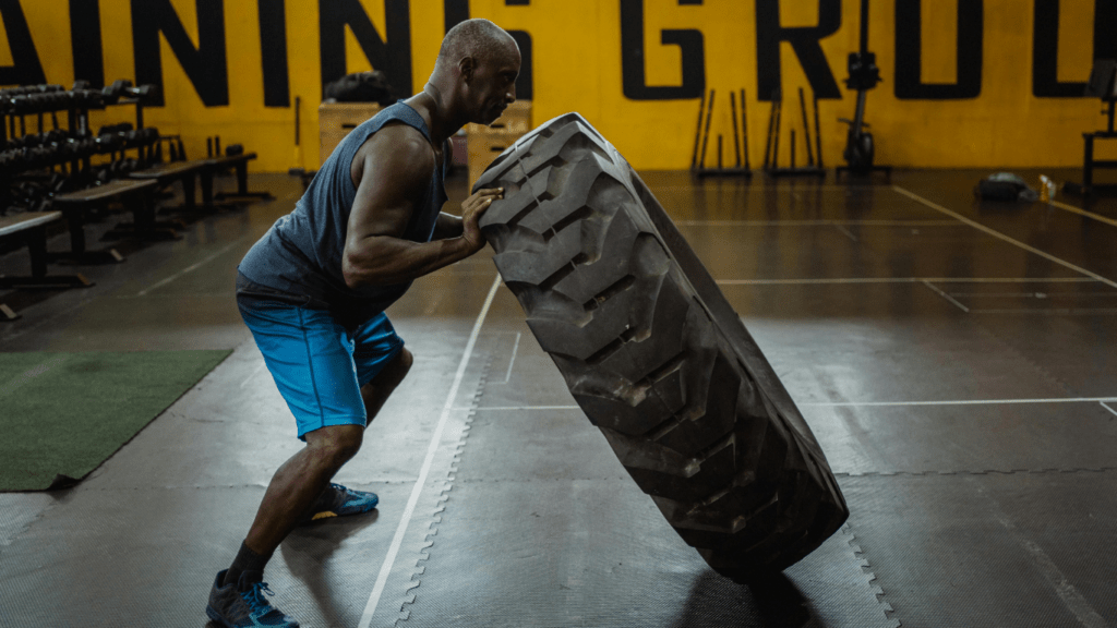 a person is lifting a large tire in a gym