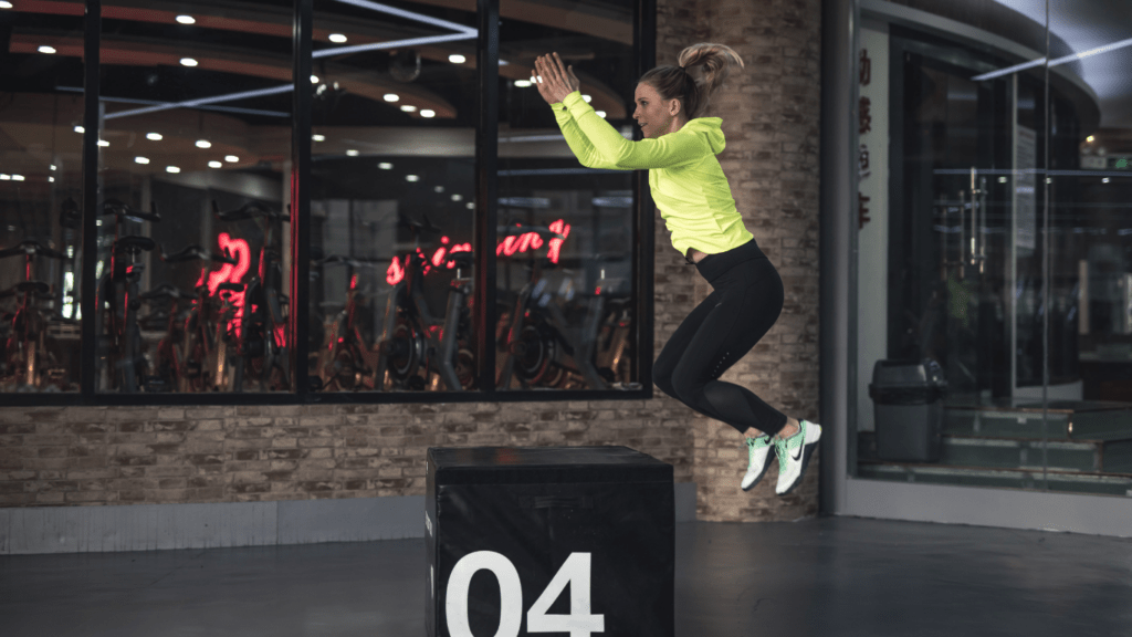 A person jumping over a wooden box in a gym