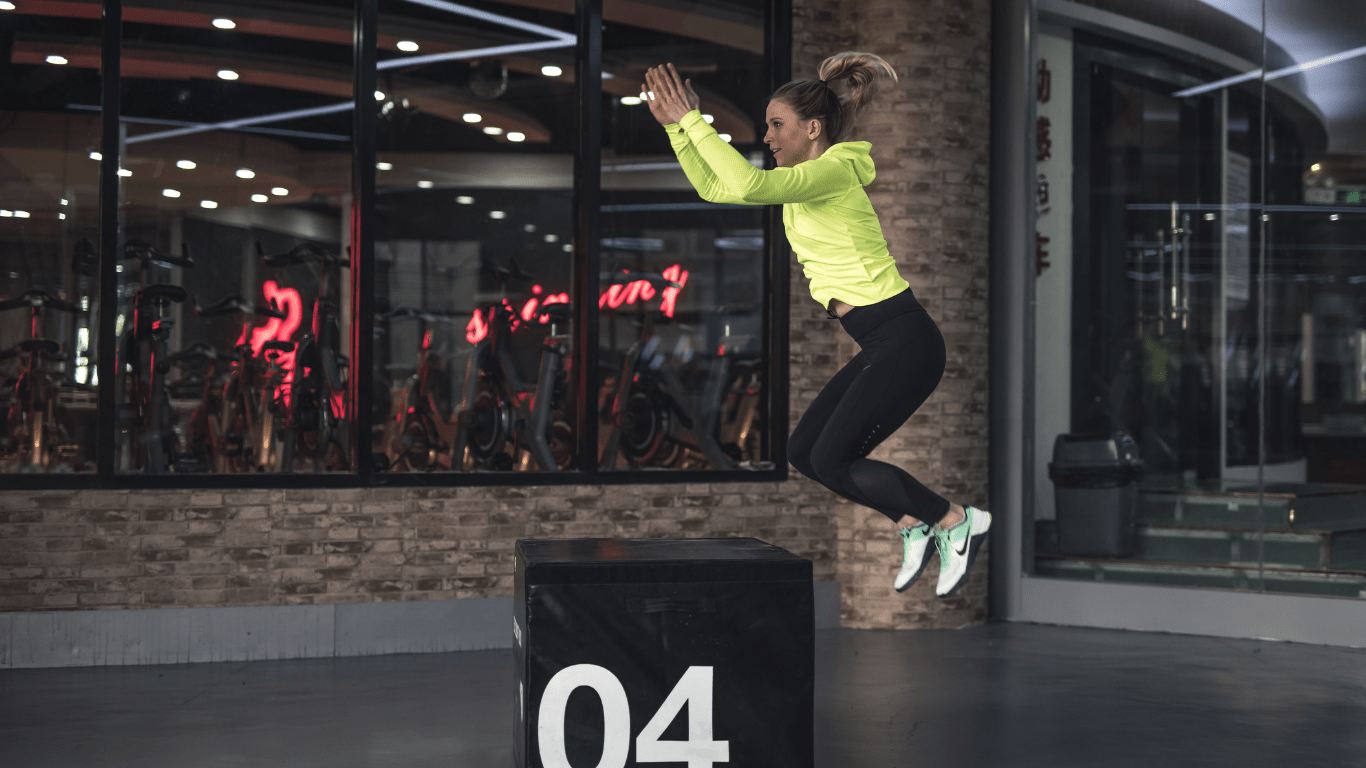 A person jumping over a wooden box in a gym