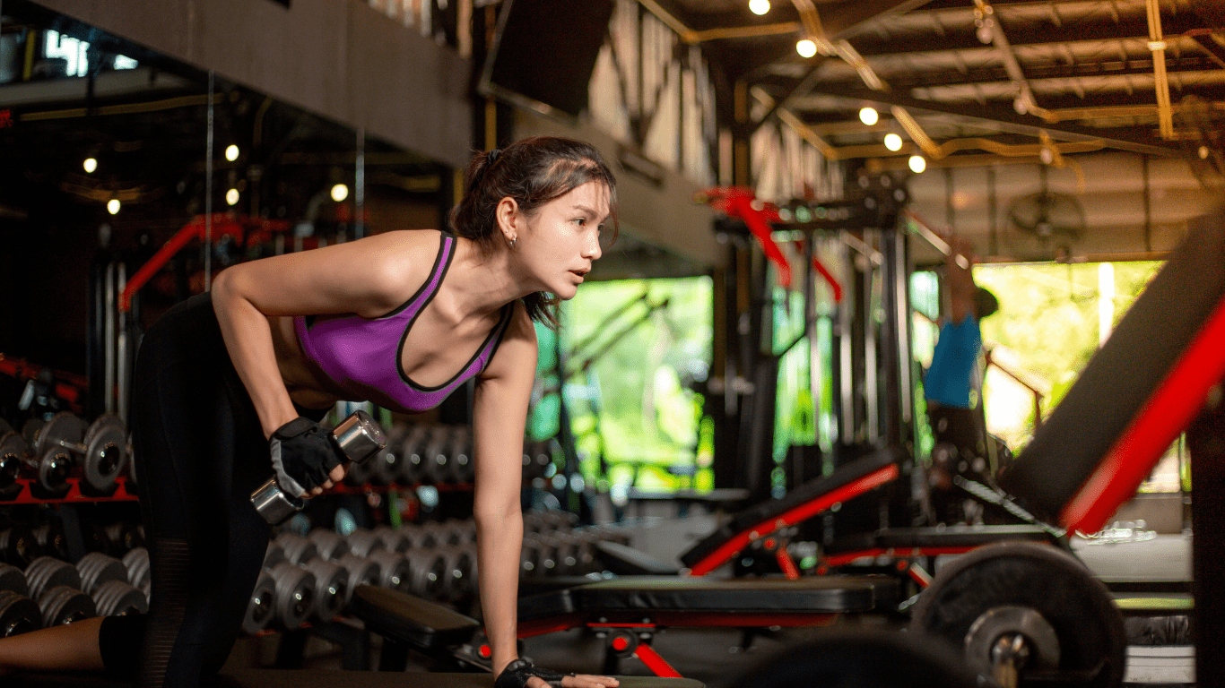 A person doing pushups with dumbbells in a gym