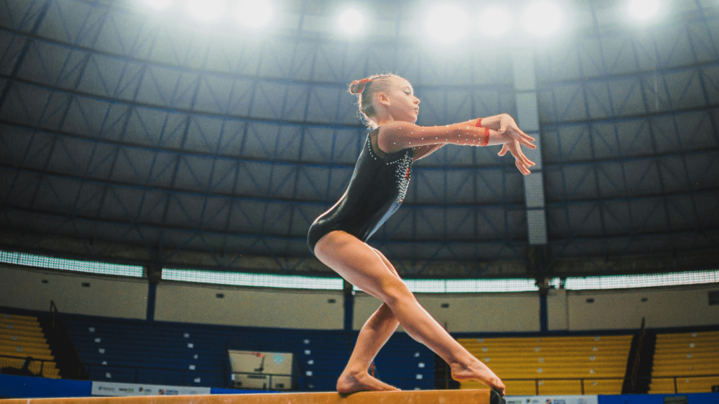 a girl on a balance beam in an indoor arena
