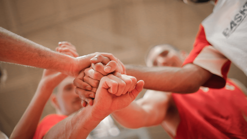 a group of people holding hands together in a basketball game