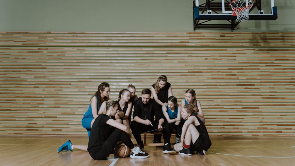 a group of people sitting on a basketball court