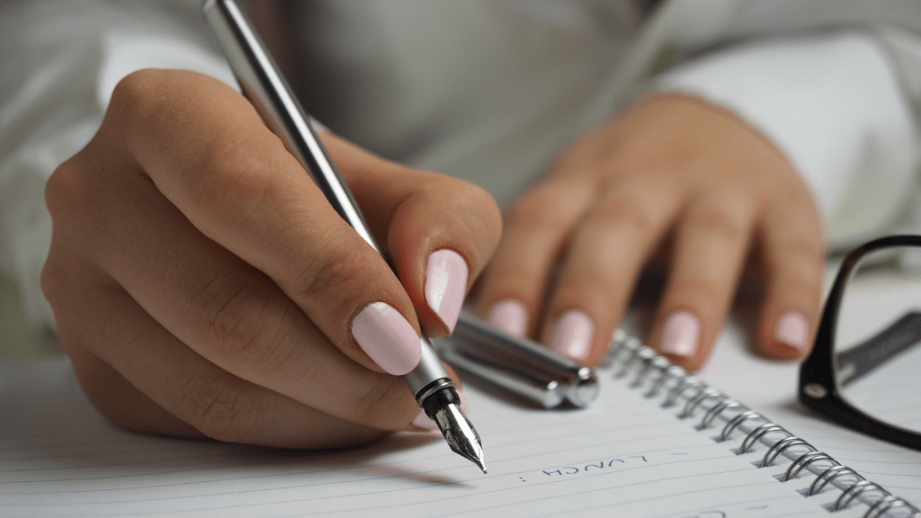 a person is writing on a notepad with a pen