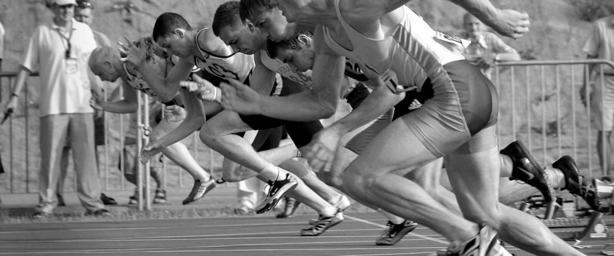 spot-runs-start-la-34514 Athletes burst from the blocks during a sprint race, captured in monochrome.